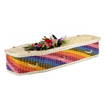 A rainbow wicker coffin with vibrant diagonal strips across the body and a natural light willow lid. The coffin is a traditional six sided shape.